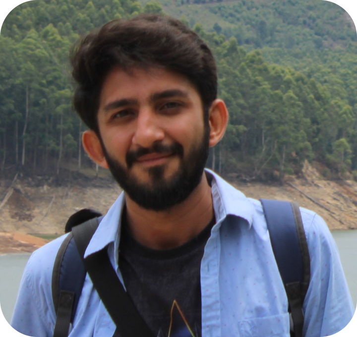 Malay Oza, Founder of ForestRP, standing outdoors with a backpack against a forest and lake backdrop